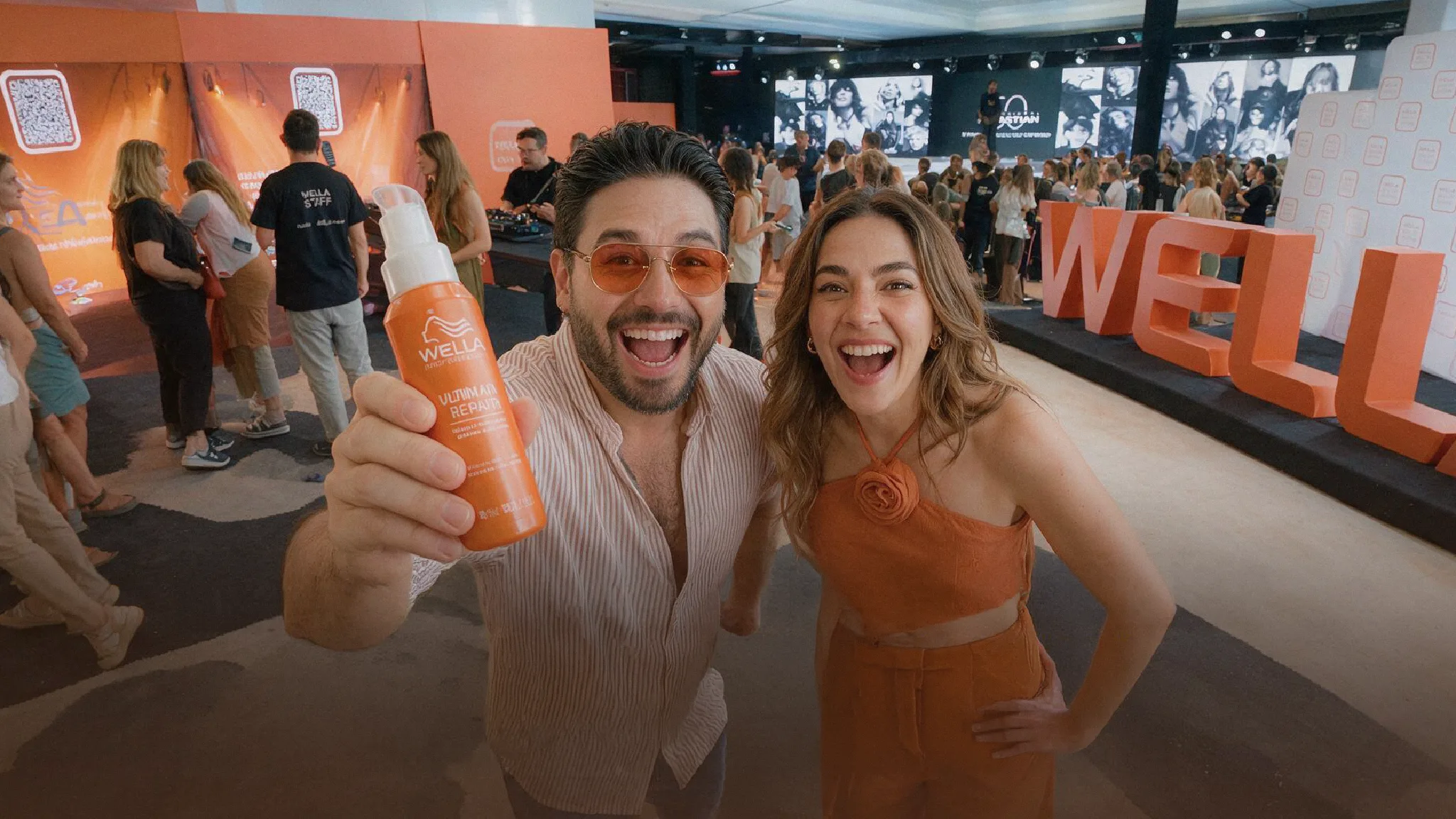 Asistentes a un evento de Wella con el producto en mano frente al escenario